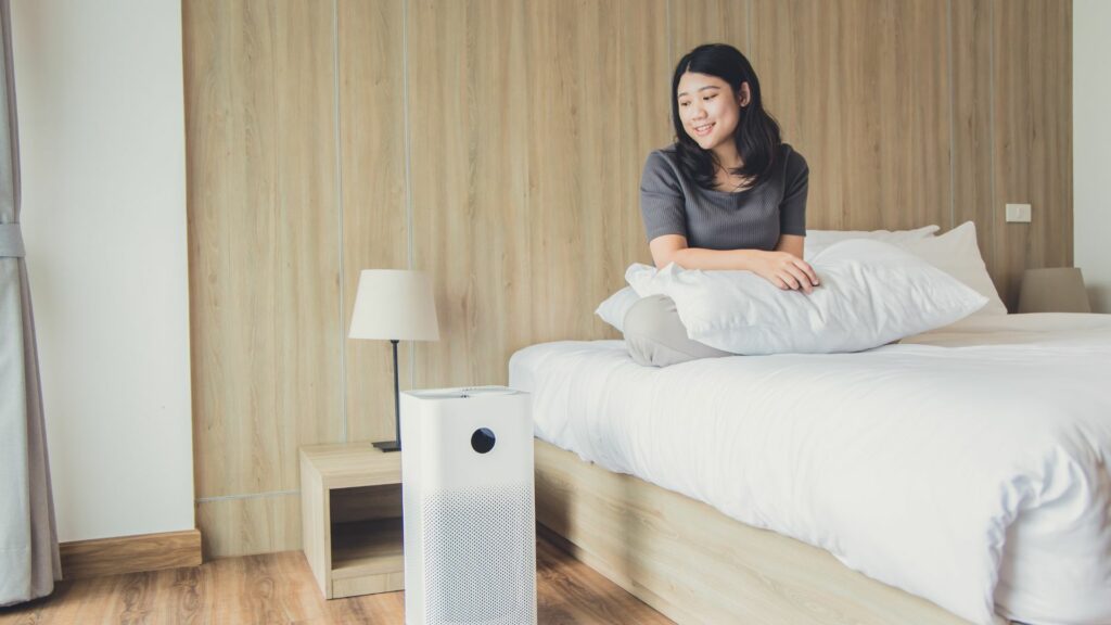 A woman who learned how to improve indoor air quality admires the air filtering device beside her bed. 